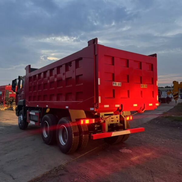 Rear view of red HOWO NX 371HP dump truck showing the large tipper cargo box, illuminated tail lights, and robust rear bumper