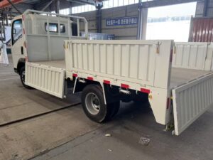 Rear view of a white SINOTRUK HOWO 4x2 light cargo truck with its side-drop cargo box gates open, showcasing the payload area - HICA Vehicle