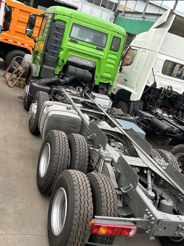 Left rear view of green SINOTRUK HOWO TX 8x4 cargo truck chassis showing frame and suspension