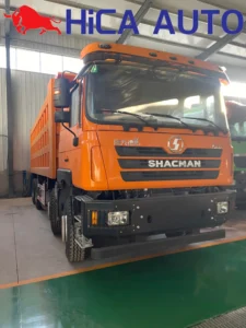 Left front side view of orange SHACMAN F3000 8x4 dump truck with mining steel bumper